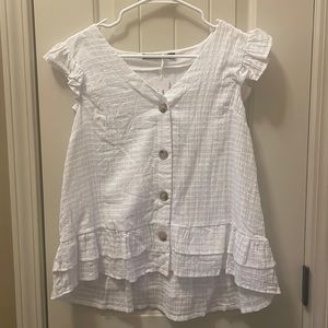 Women’s white button down blouse with ruffled edge.